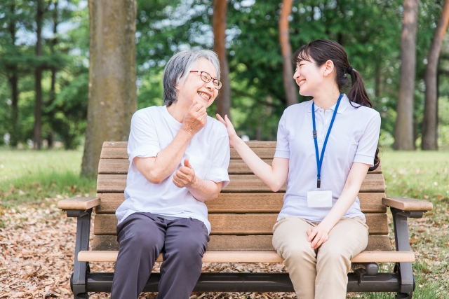 公園で話す高齢者と笑顔の介護スタッフ女性